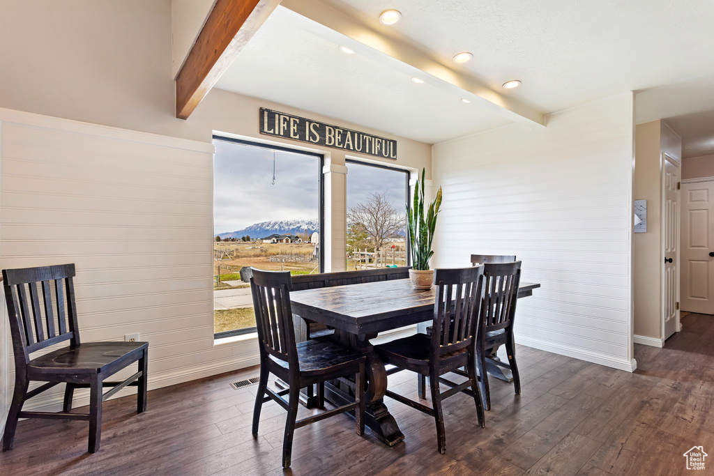 Dining space with a mountain view, dark hardwood / wood-style floors, and beam ceiling