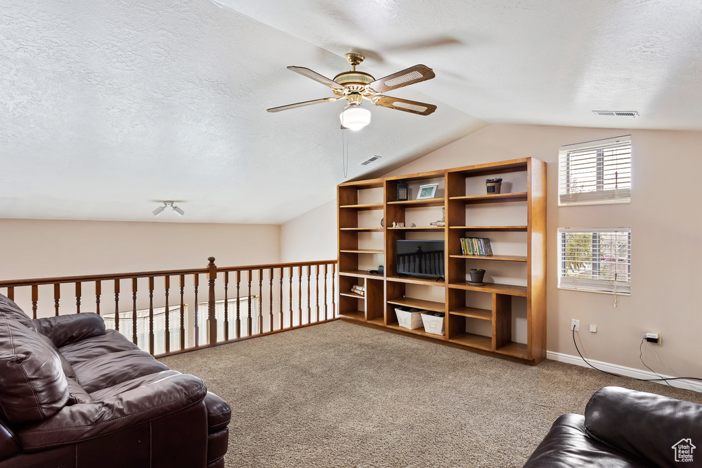 Carpeted living room featuring lofted ceiling, a textured ceiling, and ceiling fan