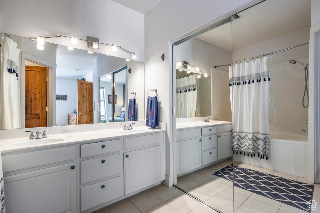 Bathroom featuring tile floors, shower / bath combination with curtain, and dual vanity