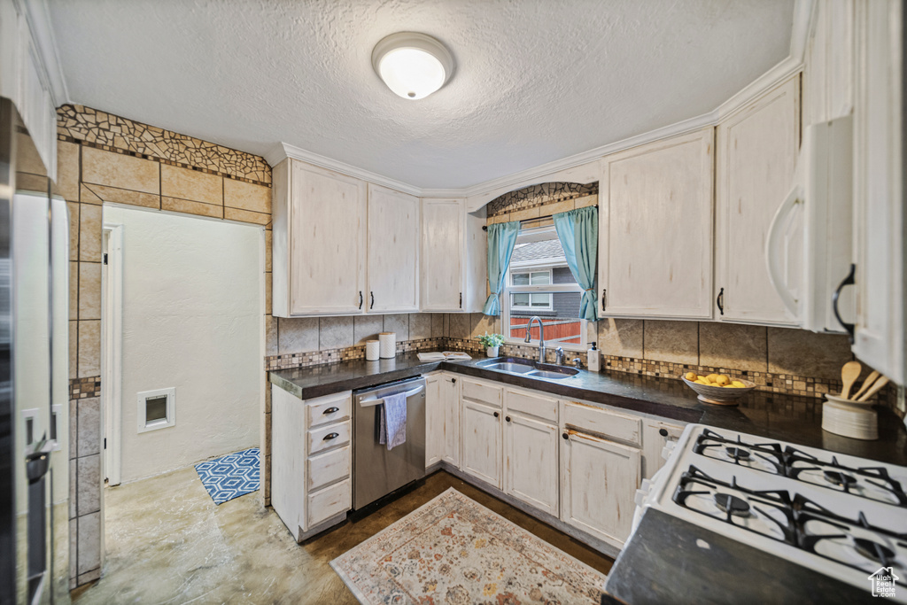 Kitchen featuring a textured ceiling, tasteful backsplash, light tile flooring, white appliances, and sink