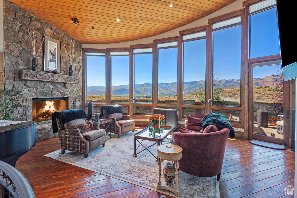 Living room featuring a mountain view, dark hardwood / wood-style flooring, a stone fireplace, and vaulted ceiling
