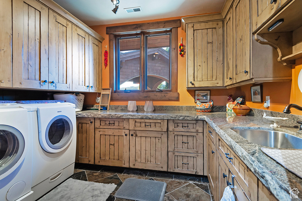 Washroom with cabinets, dark tile floors, sink, and independent washer and dryer