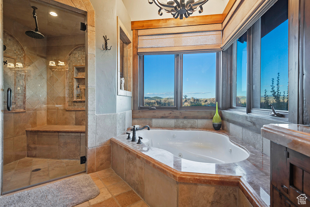 Bathroom with a notable chandelier, tile flooring, and separate shower and tub