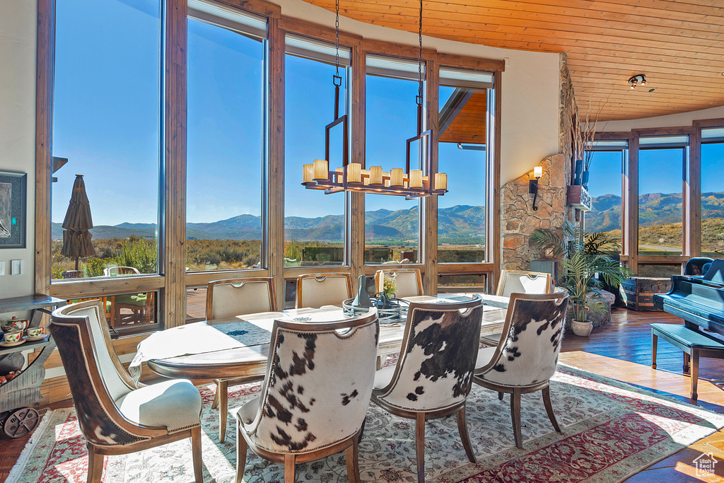 Sunroom featuring a notable chandelier, a mountain view, and wooden ceiling