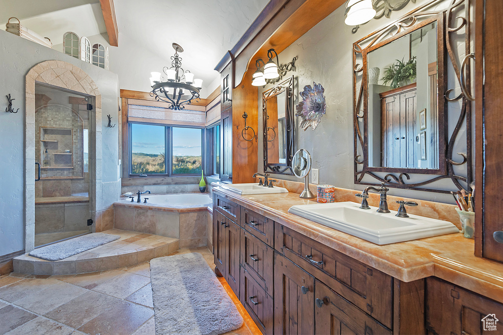 Bathroom with a notable chandelier, double vanity, tile floors, and separate shower and tub
