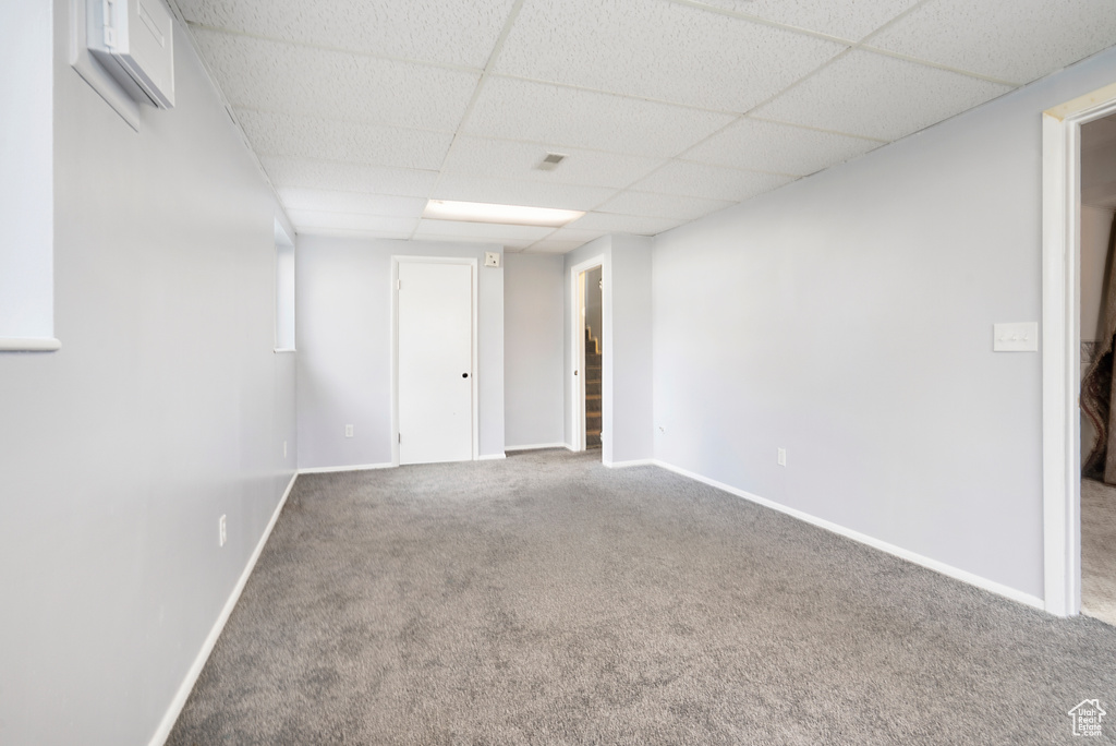 Empty room with carpet floors and a paneled ceiling
