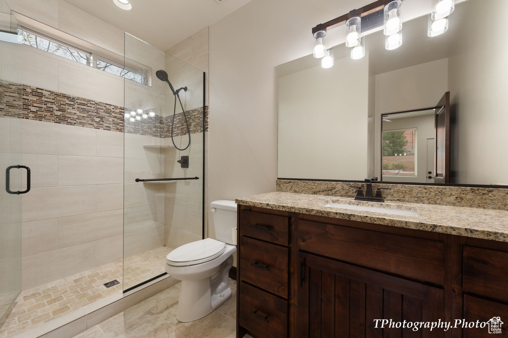 Bathroom with an enclosed shower, tile flooring, large vanity, and toilet