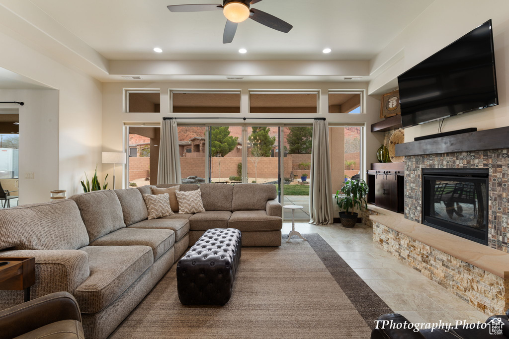 Tiled living room with a stone fireplace and ceiling fan