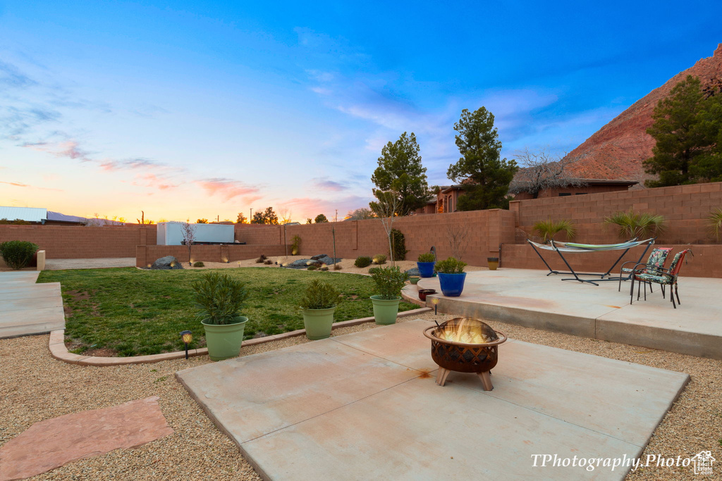 Patio terrace at dusk featuring an outdoor fire pit
