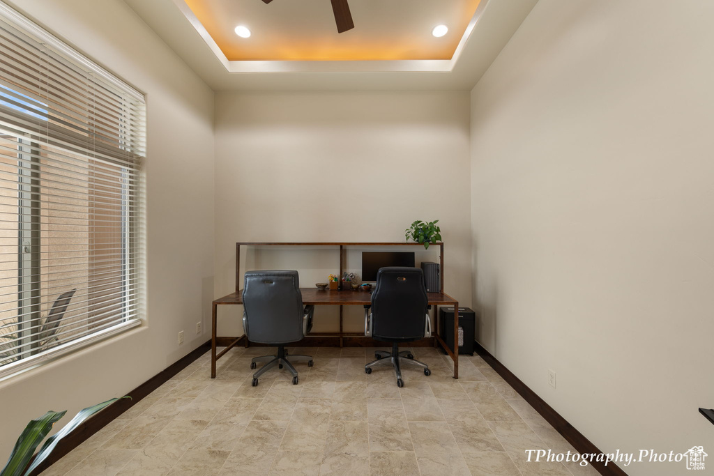 Tiled home office with ceiling fan and a raised ceiling