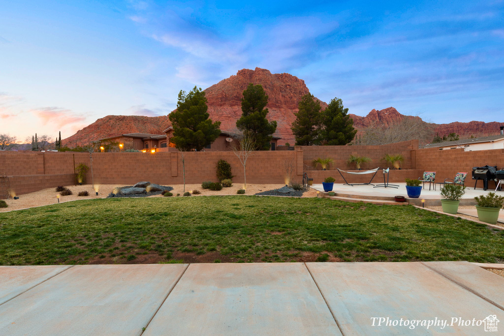 Yard at dusk with a patio area and a mountain view