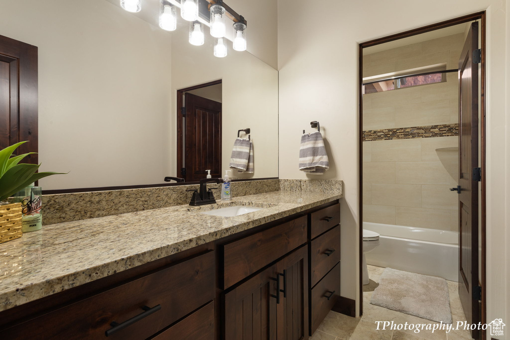 Full bathroom with vanity, toilet, tiled shower / bath combo, and tile flooring