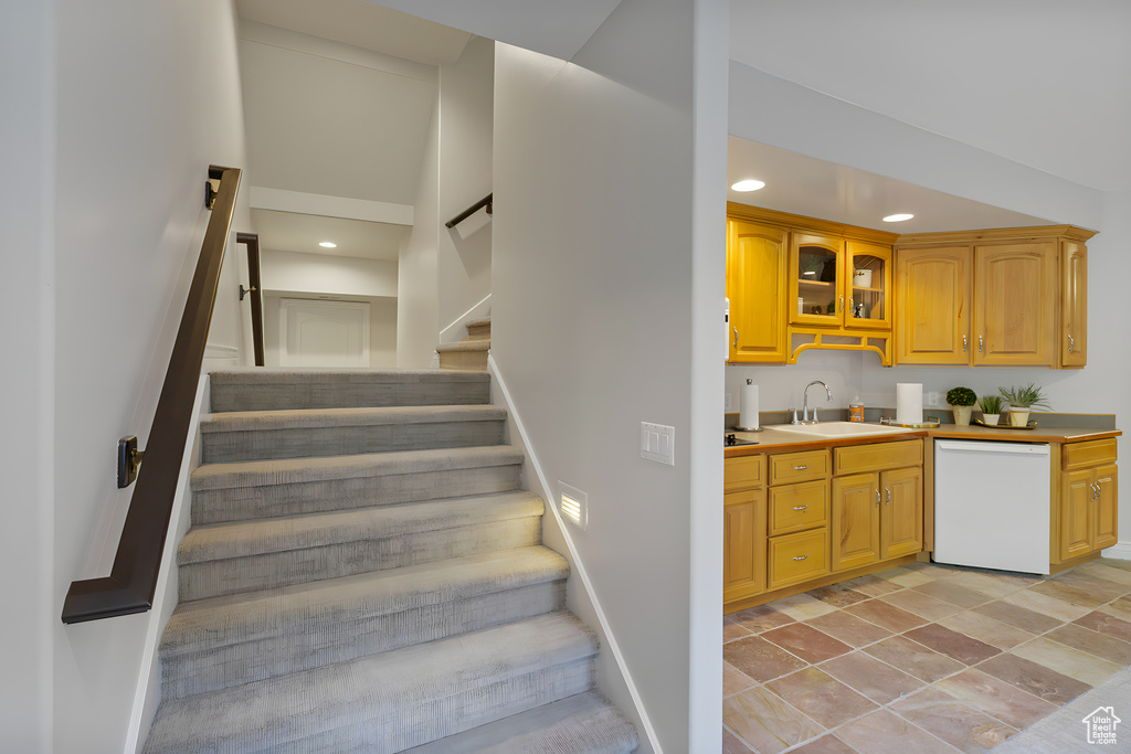 Stairs featuring light tile flooring, a towering ceiling, and sink