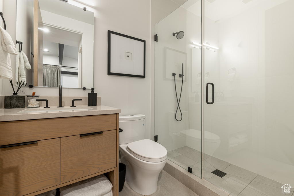 Bathroom with an enclosed shower, toilet, tile floors, and vanity with extensive cabinet space