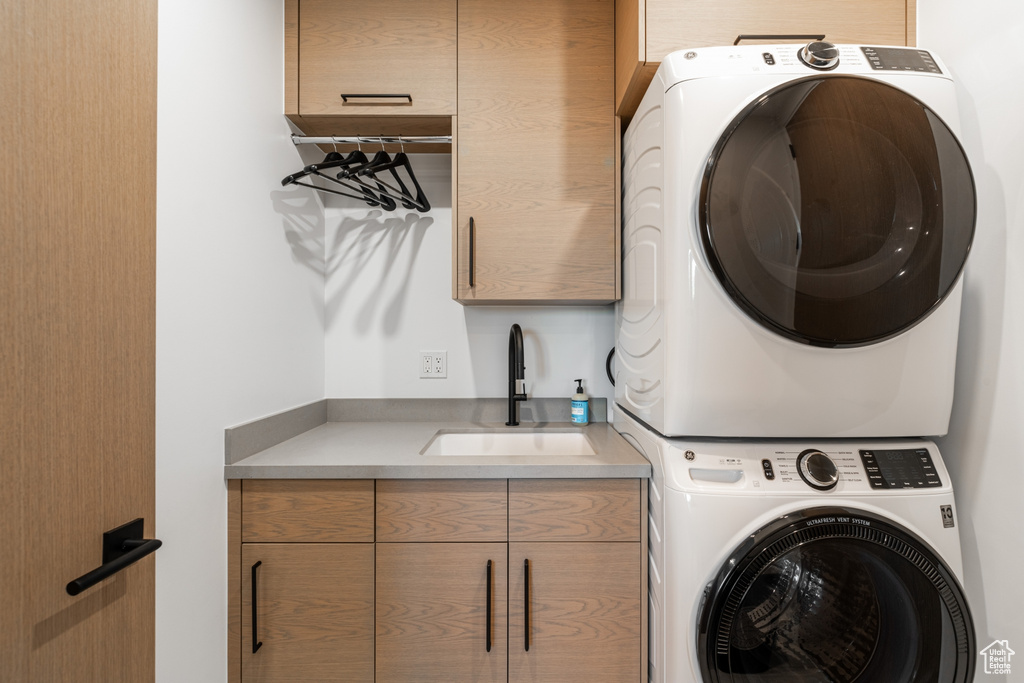 Laundry room with sink, cabinets, and stacked washer / drying machine