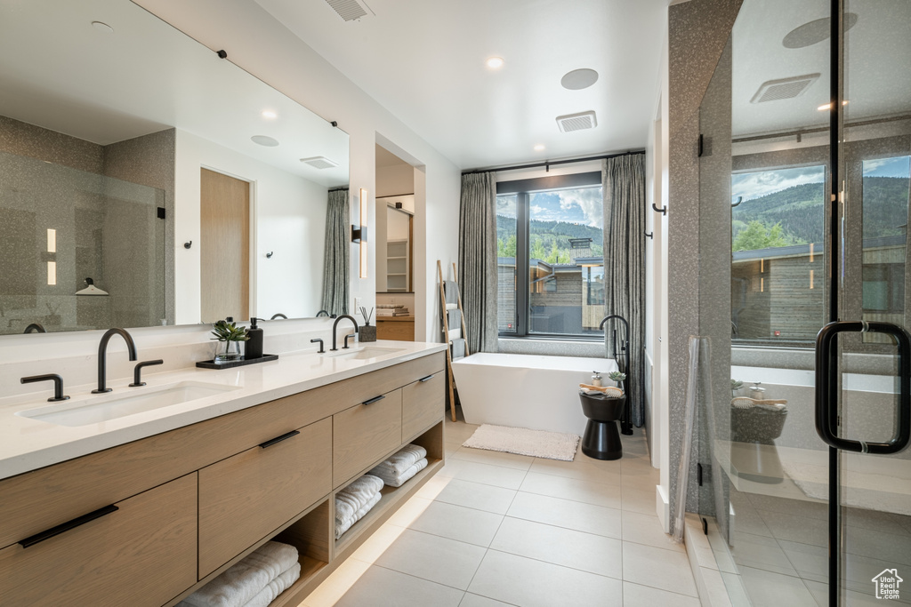 Bathroom featuring double sink vanity, tile flooring, and plus walk in shower