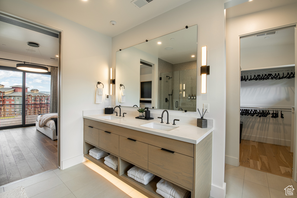 Bathroom with walk in shower, hardwood / wood-style floors, dual sinks, and vanity with extensive cabinet space