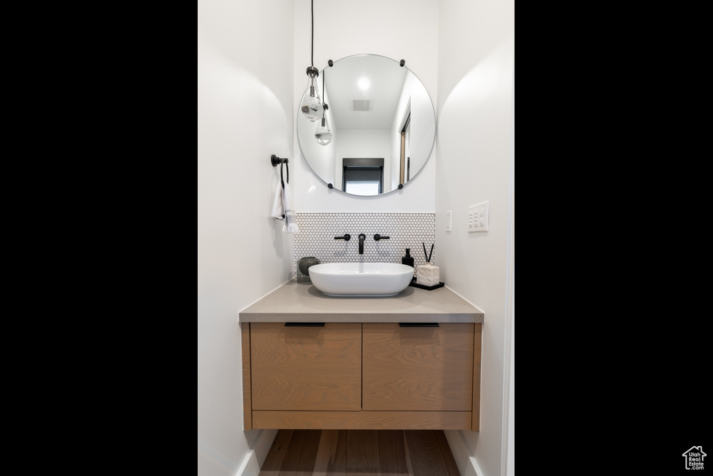 Bathroom featuring vanity, tasteful backsplash, and hardwood / wood-style floors