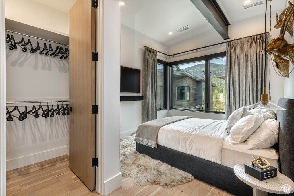 Bedroom featuring beam ceiling, a closet, and light hardwood / wood-style flooring