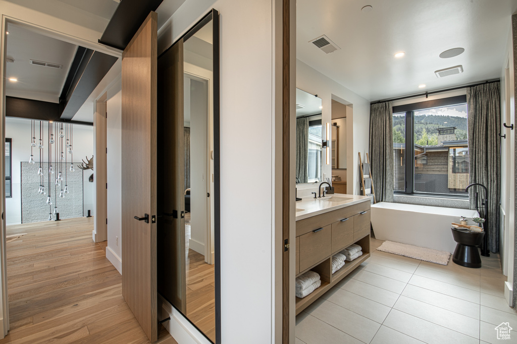 Bathroom featuring a washtub, tile floors, and vanity