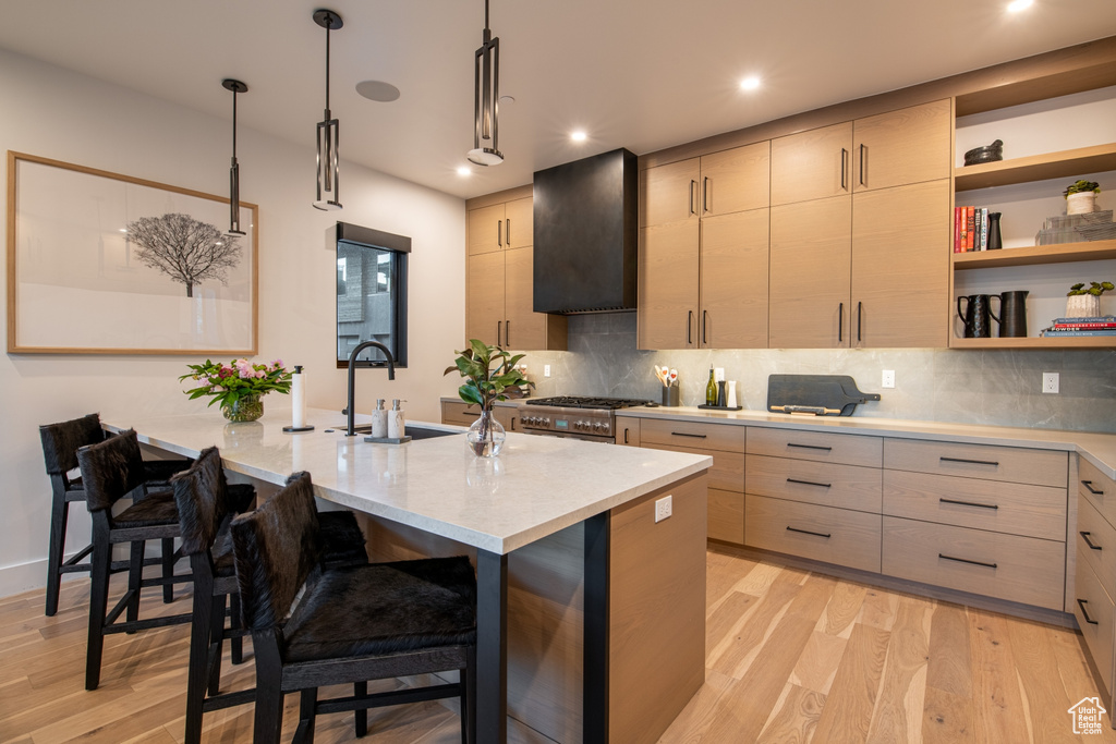 Kitchen with a kitchen breakfast bar, tasteful backsplash, decorative light fixtures, and light wood-type flooring