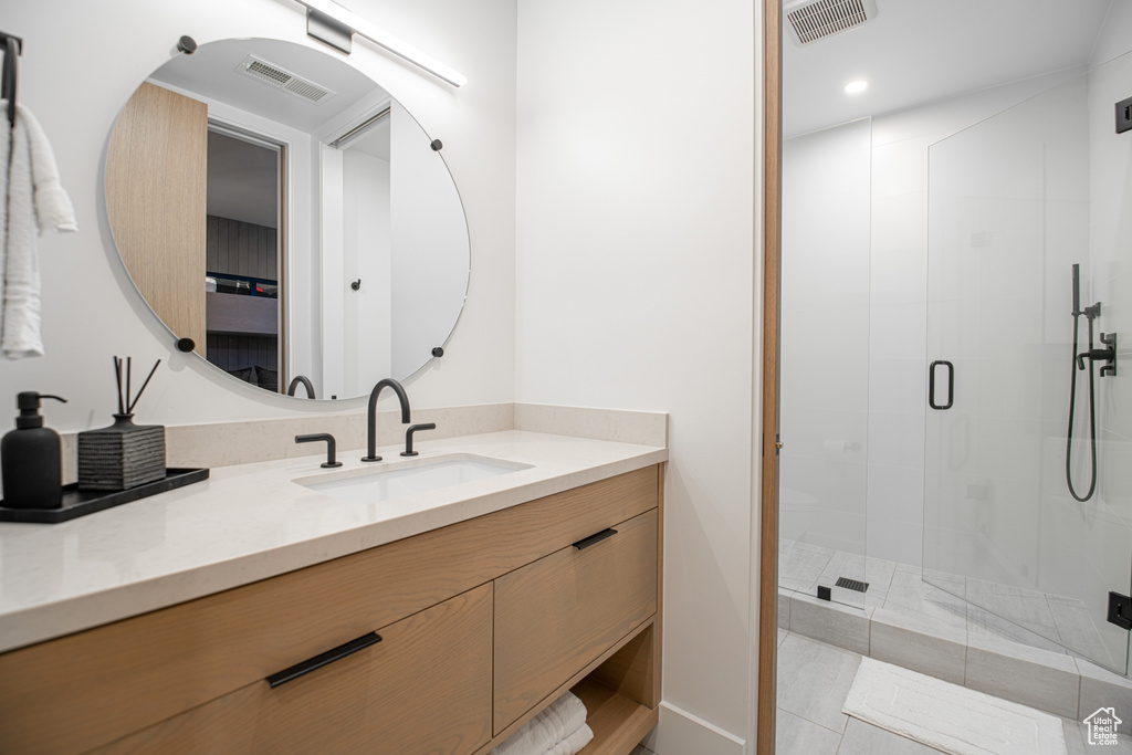 Bathroom featuring walk in shower, tile floors, and vanity