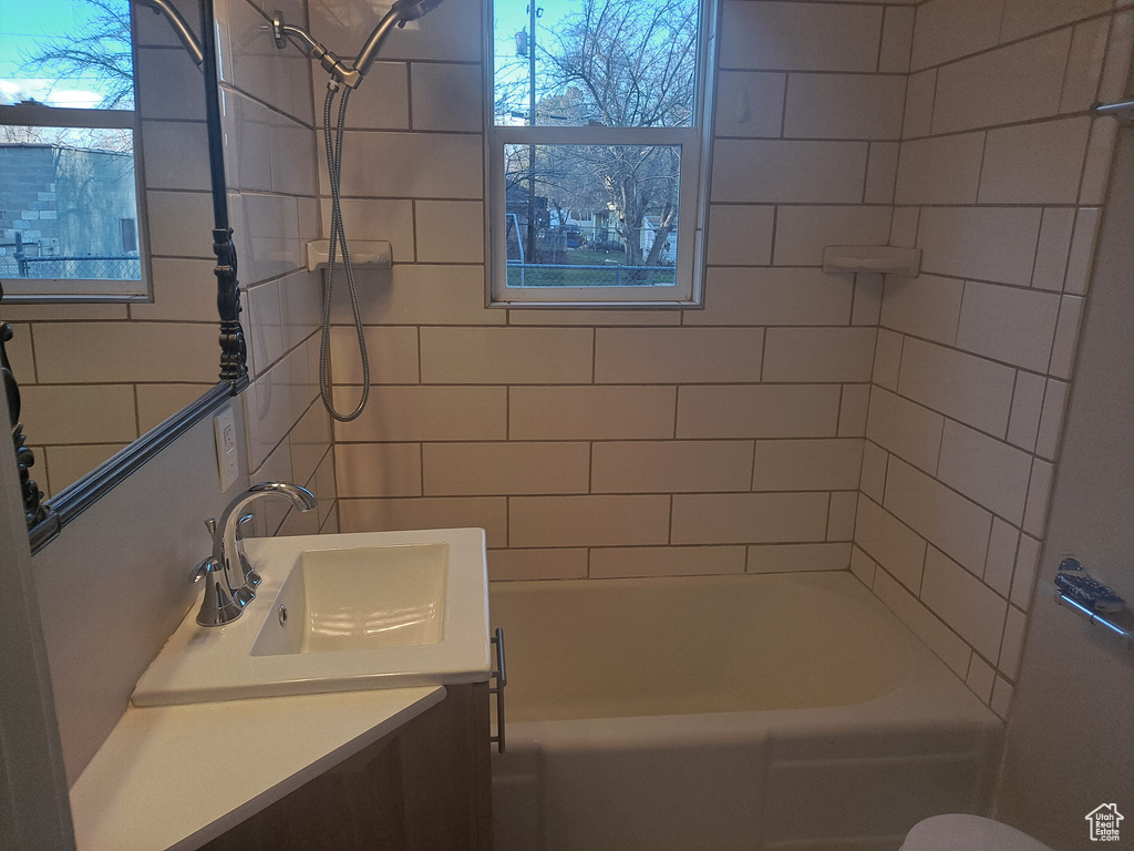 Bathroom featuring plenty of natural light, oversized vanity, and tiled shower / bath combo