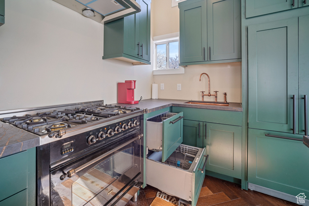Kitchen with green cabinetry, sink, double oven range, and dark parquet floors