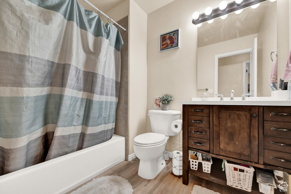 Full bathroom featuring vanity, toilet, hardwood / wood-style flooring, and shower / bath combination with curtain