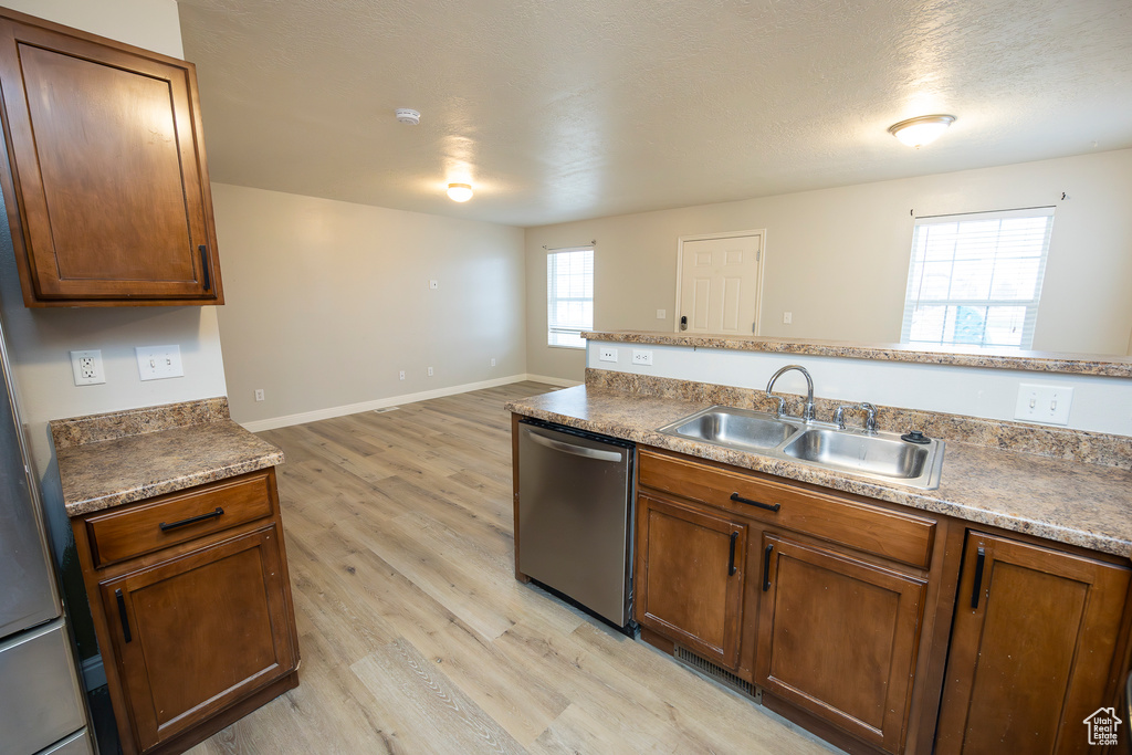 Kitchen featuring stainless steel dishwasher, light hardwood / wood-style floors, and sink