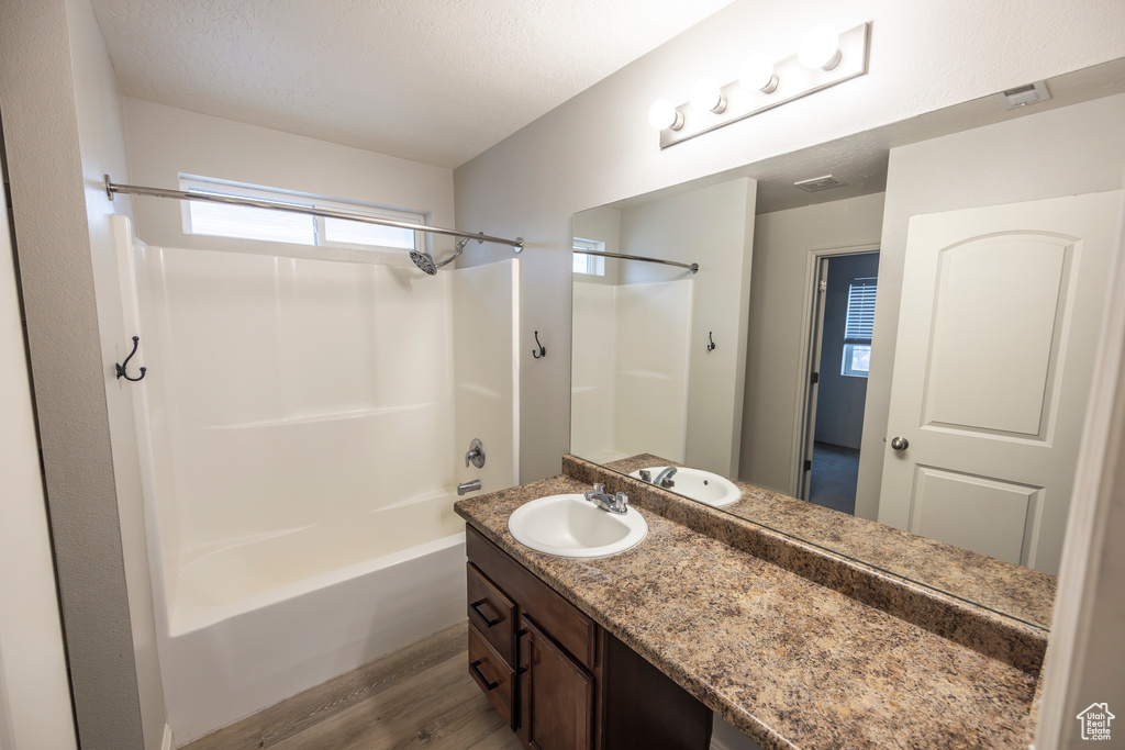 Bathroom with hardwood / wood-style flooring, vanity with extensive cabinet space, and bathtub / shower combination