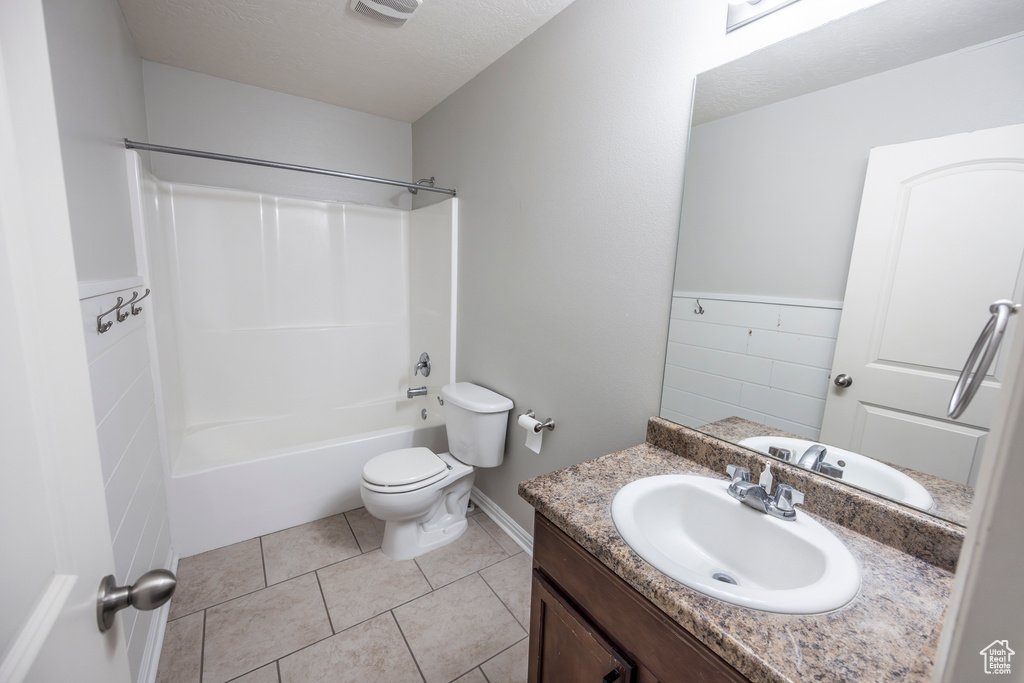 Full bathroom with vanity, a textured ceiling, toilet, tile floors, and shower / bath combination