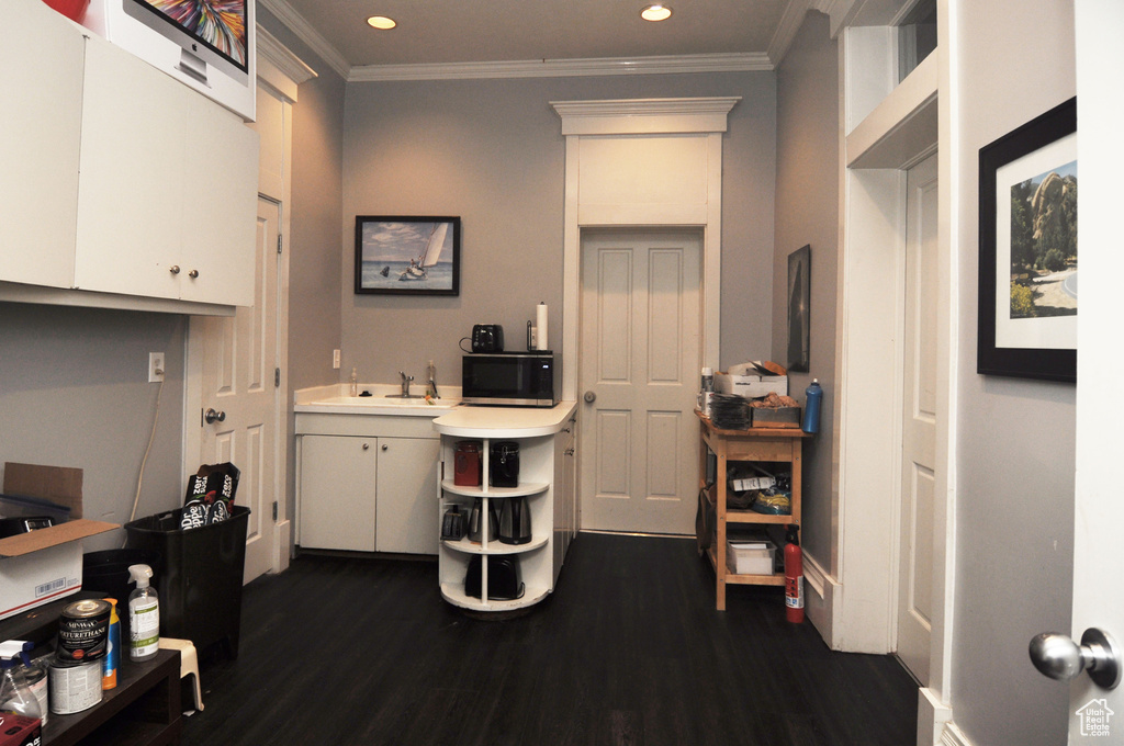 Home office with ornamental molding, dark hardwood / wood-style flooring, and sink