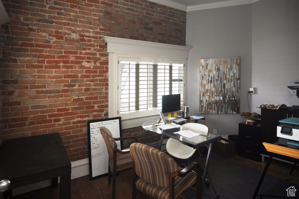 Dining room featuring crown molding, brick wall, and dark hardwood / wood-style flooring