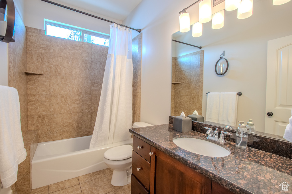 Full bathroom featuring vanity with extensive cabinet space, tile floors, shower / bath combo with shower curtain, and toilet