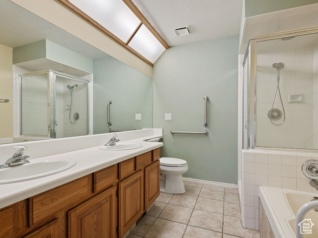 Full bathroom with tile flooring, separate shower and tub, dual vanity, a textured ceiling, and toilet