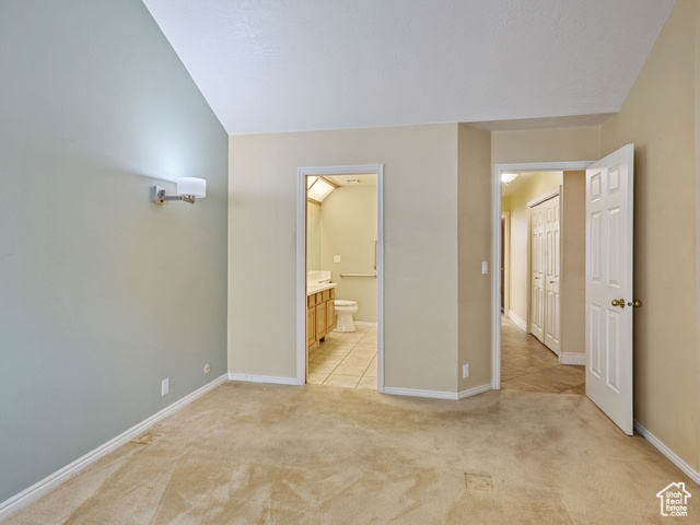 Unfurnished bedroom featuring light colored carpet and ensuite bathroom