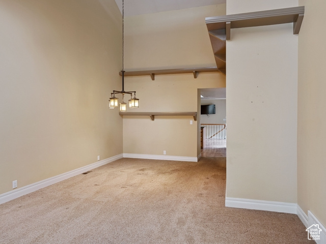 Interior space with a chandelier, carpet, and lofted ceiling