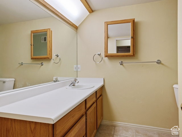 Bathroom with tile floors, vanity with extensive cabinet space, and toilet