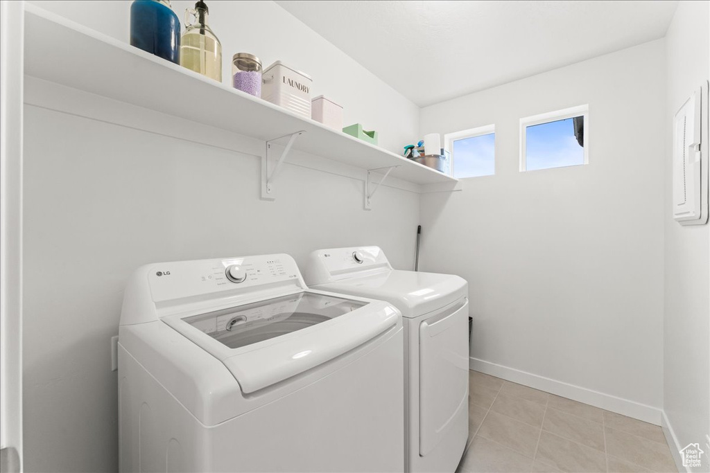 Clothes washing area with light tile flooring and separate washer and dryer
