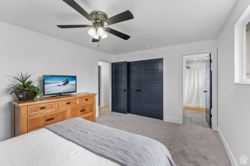 Carpeted bedroom with a closet, ensuite bathroom, and ceiling fan