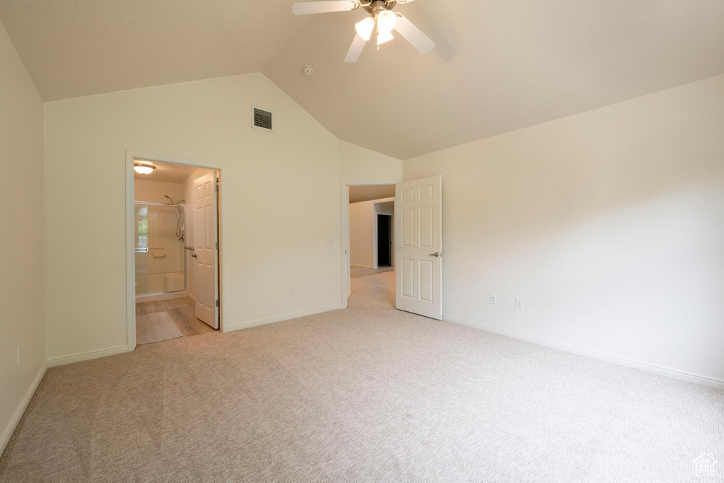 Unfurnished bedroom featuring ensuite bath, ceiling fan, vaulted ceiling, and carpet