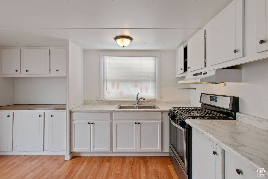 Kitchen featuring white cabinets, light wood-type flooring, stainless steel range with gas stovetop, and sink