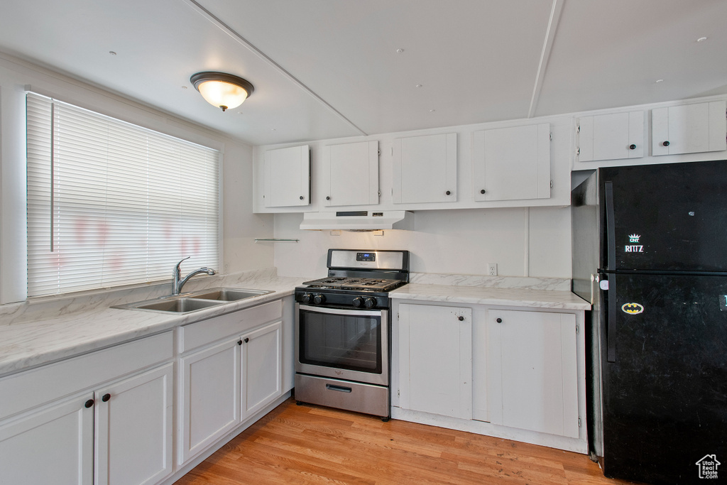 Kitchen featuring white cabinetry, light wood-type flooring, gas range, and sink