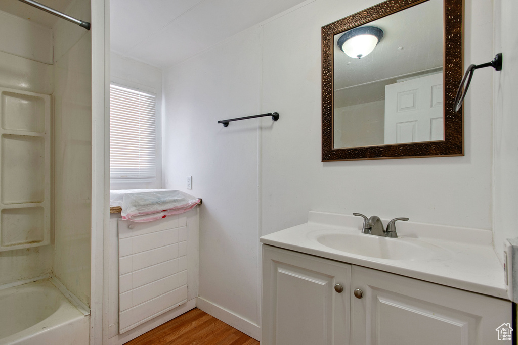 Bathroom with hardwood / wood-style floors, vanity, and washtub / shower combination