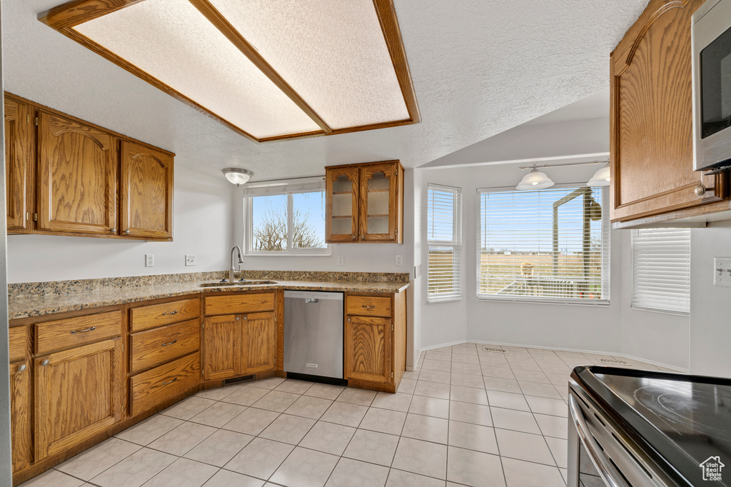 Kitchen featuring sink, stainless steel appliances, light tile floors, and a wealth of natural light