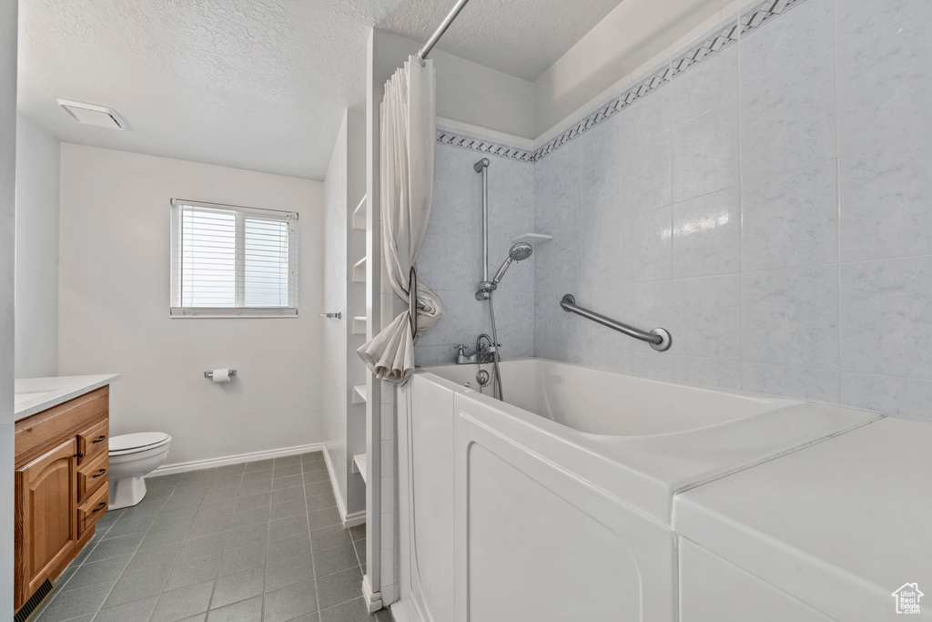 Full bathroom with a textured ceiling, tile floors, vanity, toilet, and shower / tub combo