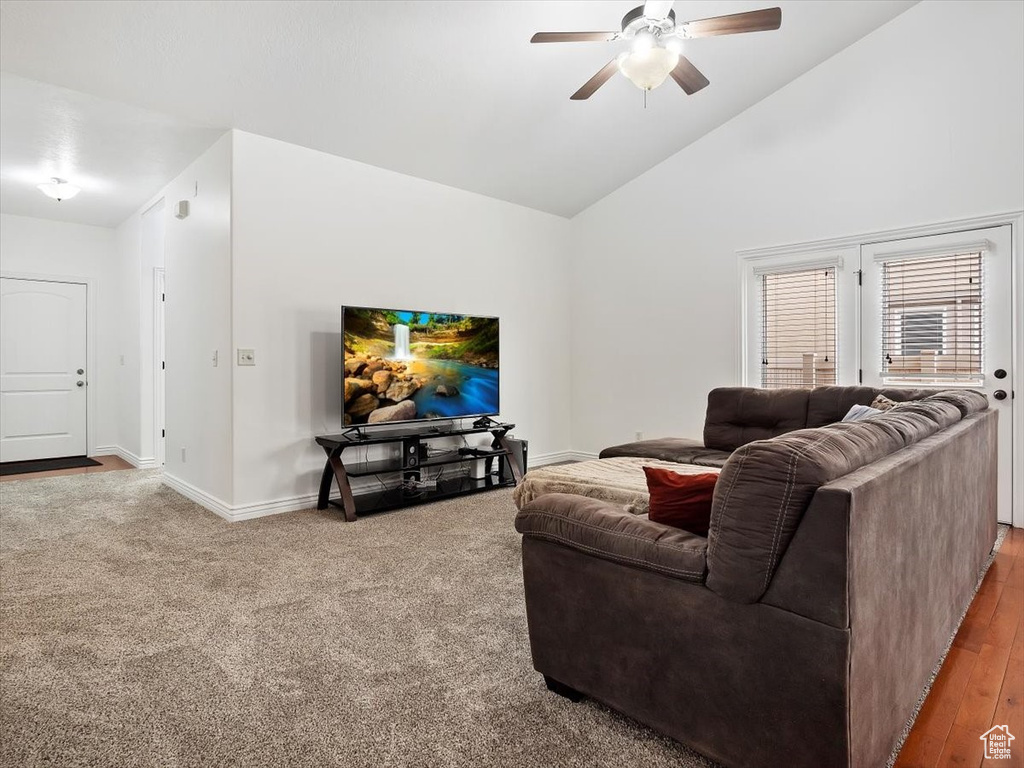 Living room with high vaulted ceiling, light carpet, and ceiling fan