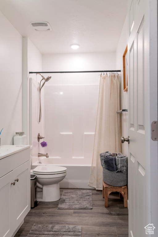 Full bathroom featuring shower / bathtub combination with curtain, hardwood / wood-style flooring, toilet, and vanity