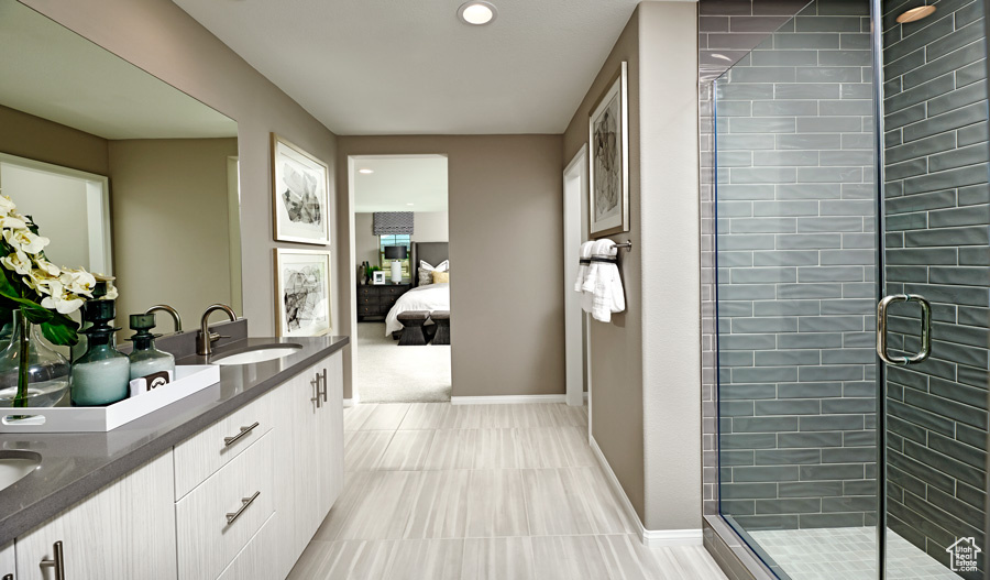 Bathroom with an enclosed shower, double sink vanity, and tile floors
